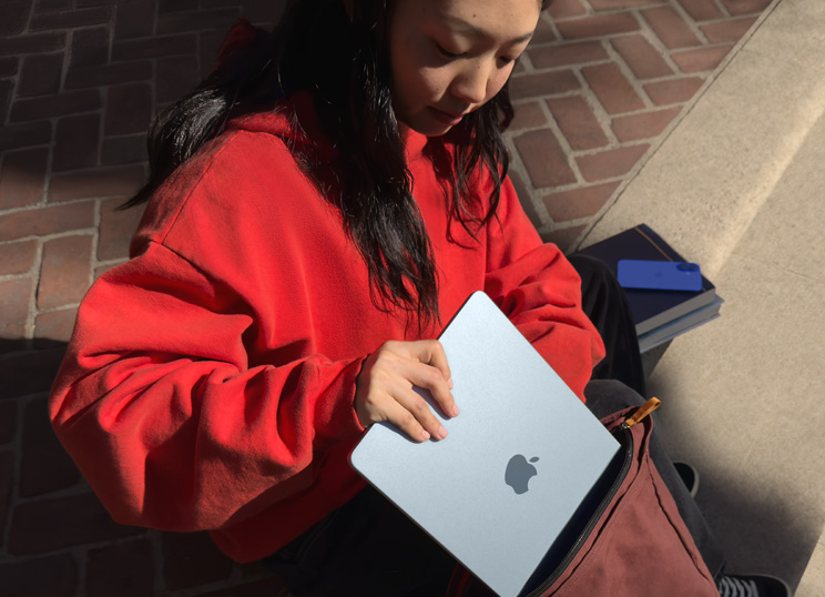 A Student placing MacBook into backpack.