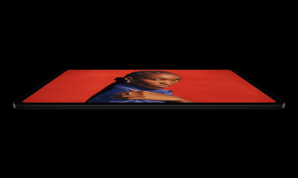 iPad Pro, vue latérale, orientation paysage, noir sidéral, angles arrondis, cadre d’écran noir, écran affichant un fond rouge vif avec une personne en chemise bleue posant la main sur son épaule