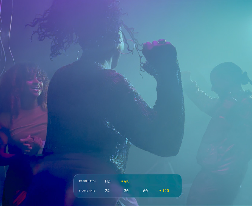Egy kijelzőn három ember táncol gyenge megvilágításban. A képi anyag a 4K-s, 120 képkocka/s sebességű Dolby Vision-videofelvétel lehetőségeit illusztrálja.